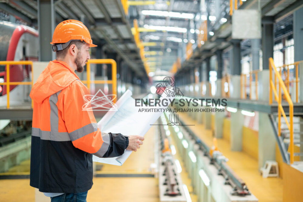 работник изучает проект стоя в производственном помещении