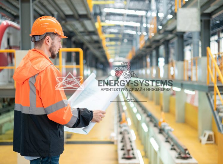 работник изучает проект стоя в производственном помещении
